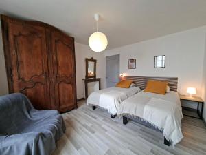 a bedroom with two beds and a large wooden cabinet at Maison de campagne - Granges sur Lot in Granges-sur-Lot