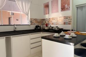 a kitchen with white cabinets and black counter tops at Completa e próxima ao Acqualinda in Andradina