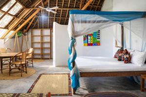 a bed in a room with a table and chairs at Villa Kiota in Paje