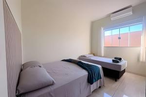 a white bedroom with a bed and a window at Completa e próxima ao Acqualinda in Andradina