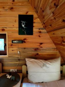 a room with a wooden wall with a bed and a ceiling at Utopija Cabin by Vilovi Botić in Nova Varoš