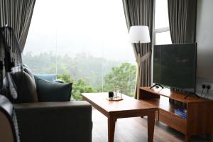 a living room with a couch and a tv and a table at RuKu Villa Pussellawa in Pussellawa