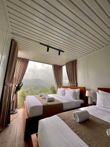 a bedroom with two beds and a large window at RuKu Villa Pussellawa in Pussellawa