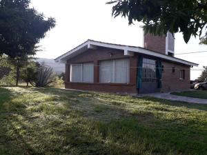 a small brick house with a green door in a yard at Chalet ARMONIA in La Falda +3 photos