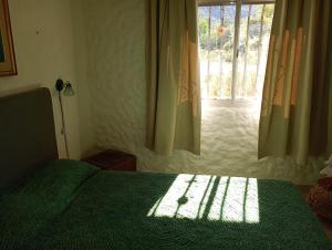 a bedroom with a green bed and a window at Chalet ARMONIA in La Falda