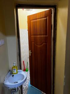 a bathroom with a sink and a wooden door at Petalluxe k24 in Narok +9 photos