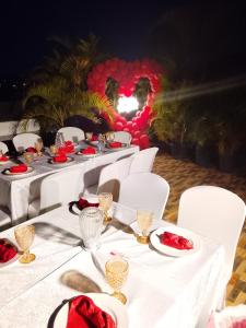 a table with white tables and chairs with red roses on them at Icon Hotel in Kampala +48 photos