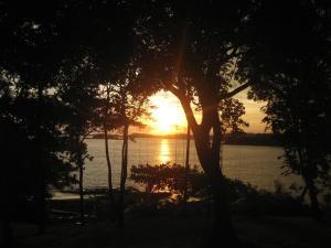 a sunset over a body of water with trees at Amazing Grace Panamá in Boca Chica