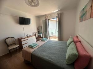 a bedroom with a bed and a chair and a window at Gori House in Madalena do Mar
