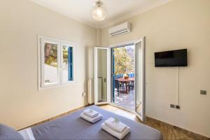 a bedroom with a bed and a tv and a window at Syros Private House with superb sea view in Kini