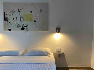 a bedroom with a bed and a painting on the wall at Daphne Bungalows in Tolo