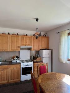 a kitchen with wooden cabinets and a white stove and a table at Wolf Chalet in Motički Gaj