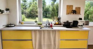 a kitchen with yellow cabinets and a sink and a window at Suur ja Hubane maja, Saaremaal in Saareküla