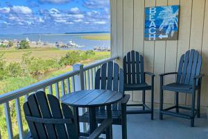 two chairs and a table on a porch with a view of the water at Bay Creek Villa - 304 in Edisto Island
