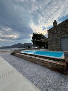 a swimming pool in front of a building with the ocean at Almira Seaside Suites in Áyios Dhimítrios