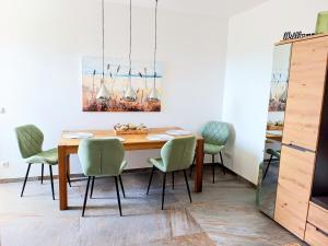a dining room with a wooden table and green chairs at Exclusive Apartment mit Alpenpanorama in Peiting