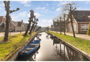 a blue boat in a canal in a village at Vakantiehuis It Loazjemint in Oostermeer