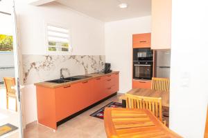 a kitchen with orange cabinets and a table and a dining room at Villa Syleone in Sainte-Marie