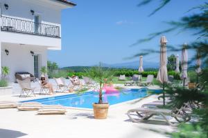 a swimming pool with chairs and people sitting around it at Vila sa bazenom Vrnjačka Idila in Vrnjačka Banja