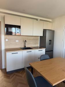 a kitchen with white cabinets and a table and a refrigerator at Guestrooms Zoya in Chernomorets