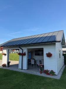 a white shed with a solar roof on a yard at Baltic Waves Ex LAZUR in Gąski