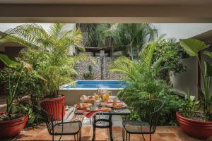 a table with food on it with plants and a pool at Casa Aura Hotel, Mérida in Mérida