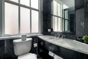 a bathroom with a toilet and a sink and windows at NoMad Studio Near Broadway & Madison Square in New York