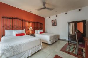 two beds in a room with red walls at Casa Aura Hotel, Mérida in Mérida +55 photos