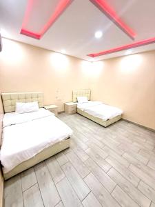 two beds in a room with red beams on the ceiling at شاليهات زارا 2 in Taif