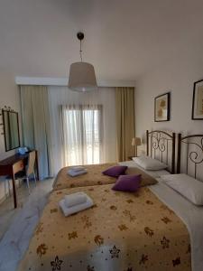a bedroom with two beds with purple pillows at Aegean Blue Studios in Afitos