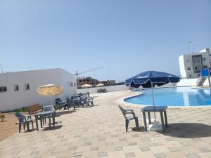 a patio with tables and chairs next to a swimming pool at Super Appartement Sidi Rhal in Dar Hamida
