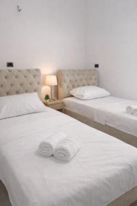 two beds in a room with white sheets and towels at Villa's Daci in Tirana