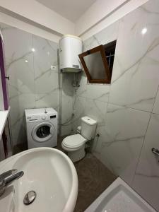 a white bathroom with a toilet and a sink at Ikon Apartments in Kashari