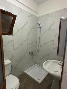 a bathroom with a shower and a toilet and a sink at Ikon Apartments in Kashari