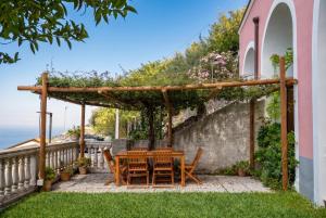 a wooden table and chairs under a pergola at Villa Belvedere Amodeo - terrace, seaview, wifi in Conca dei Marini