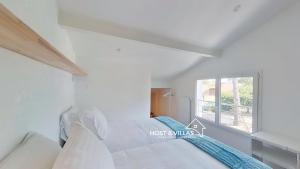 a white bedroom with a bed and a window at Host Villas LA TIRMANAISE Capbreton in Capbreton