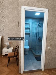 a bathroom with a shower with a toilet and a chair at Liberty Apartment And Rooms in Tbilisi City +25 photos