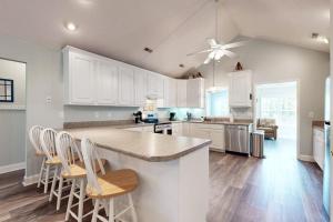 a kitchen with white cabinets and a counter with chairs at Pompano End in Edisto Island