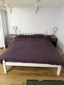 a bedroom with a large bed with a purple comforter at Countryside Studio with Private Sauna in Sacomb