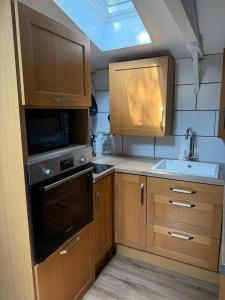 a small kitchen with wooden cabinets and a sink at Countryside Studio with Private Sauna in Sacomb