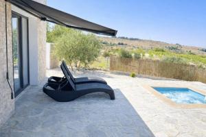 a black chair sitting on a patio next to a pool at Olivia Suite in Pano Arodes