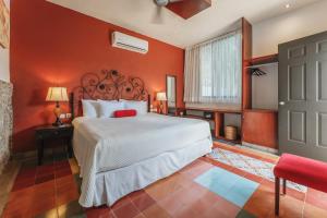 a bedroom with a bed and a red wall at Casa Aura Hotel, Mérida in Mérida