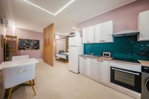 a kitchen with white cabinets and a green wall at Le Pepite Collection in Giardini Naxos