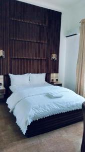 a bedroom with a large bed with white sheets at Meglams Hotel and Suite in Yenagoa