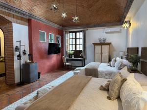 a large room with two beds and a tv at Tres Fuentes Dickinson Hotel Boutique in San Miguel de Allende