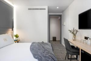 ein Schlafzimmer mit Bett, Schreibtisch und Fernseher in der Unterkunft Cal Roure Boutique Hotel in Igualada + 18 Fotos