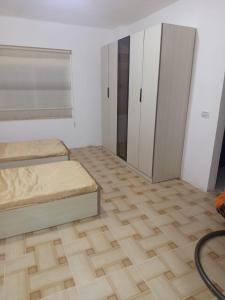 a bedroom with two beds and cabinets and a wooden floor at بيت مفروش للايجار-عجلون-اشتفينا in Ajloun