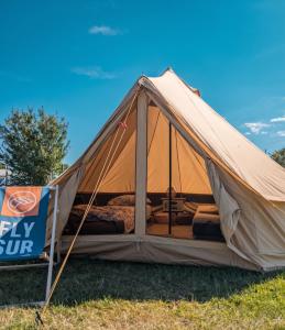 a tent with a bed and a sign in a field at Tippihostel Surfschule Kite Passion in Fehmarn