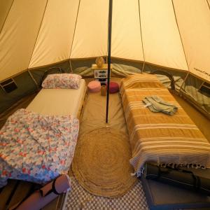 a tent with two beds and a blanket at Tippihostel Surfschule Kite Passion in Fehmarn
