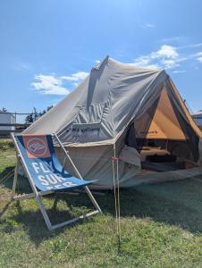 a tent with a chair and a sign in a field at Tippihostel Surfschule Kite Passion in Fehmarn
